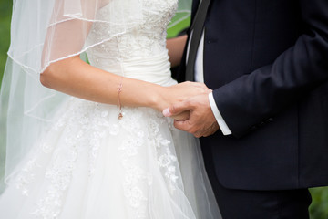 Close up shot of groom and bride holding hands and huging outdoors