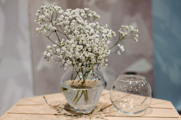 Fototapeta premium Vase with bunch of Gypsophila Baby's-breath flowers on wooden table