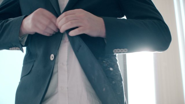 Buttoning a jacket. Stylish man in a suit fastening buttons on his jacket preparing to go out.