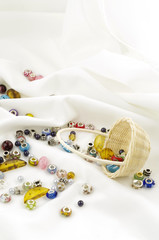 Basket of beads dropped on soft white textile background