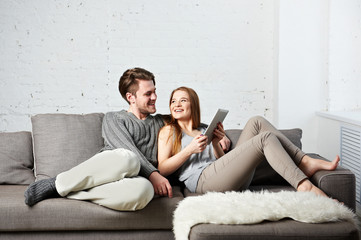 Fototapeta na wymiar Romantic relaxed young couple using tablet computer on sofa