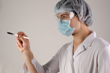 portrait of doctor in mask and hat keep scalpel on neutral background. Medcine concept.