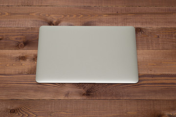 Closed silver laptop on brown wooden table