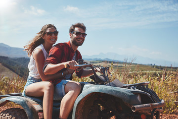 Happy young couple driving a quad bike - obrazy, fototapety, plakaty
