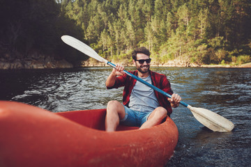 Young man kayaking on a lake - obrazy, fototapety, plakaty