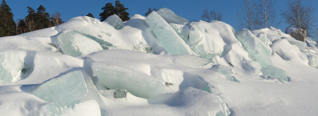 Ridge of ice boulders on a forest background.