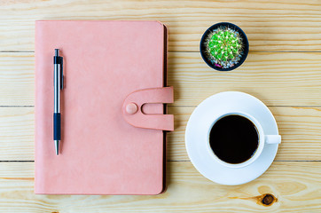 Leather notebook with pen and cup of coffee on wooden table.Top view