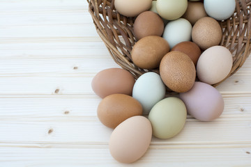 Fresh organic chickeneggs overflow out of basket on wooden backg