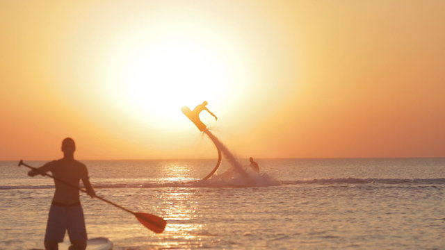 Silhouette of a Man Having Fun on Flyboard in the Sea at Sunset Background