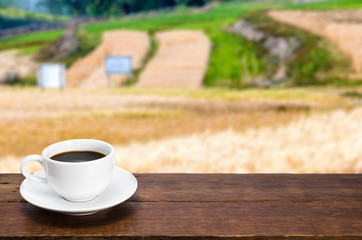 Cup of coffee  on a rustic table in barley field blurred background .close up