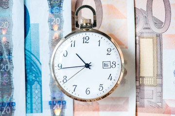 pocket watch with euro banknotes and coins