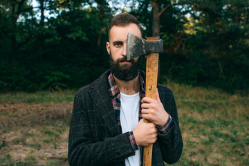 bearded  hipster  man  in the forest with ax