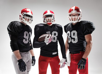 The three american football players posing with ball on white background