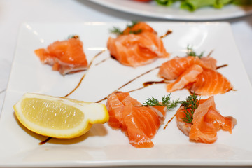 Sliced pieces of salmon and lemon on a white plate