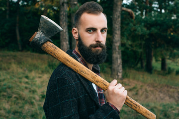 bearded  hipster  man  in the forest with ax