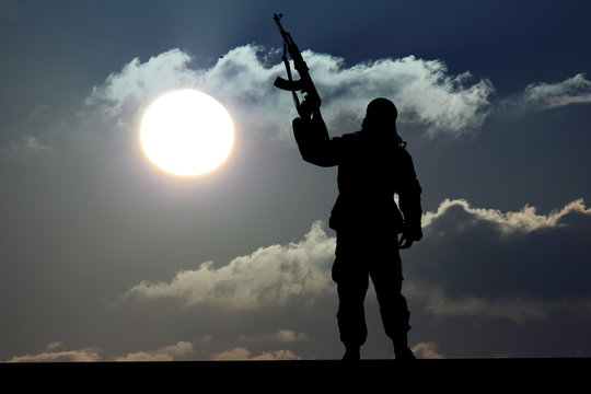 Silhouette of man with rifle during sunset