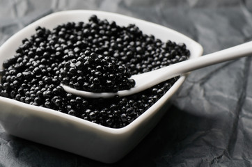 Fototapeta na wymiar spoon of black caviar in a white bowl