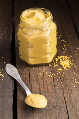 Homemade mustard sauce in a spoon and a jar