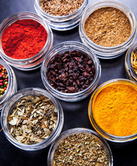 Spices on black background in special jars. Food