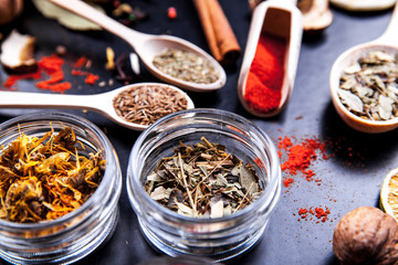 Spices on black background in special jars. Food