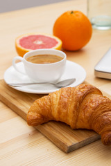 Delicious croissant with a cup of coffee and a glass of orange j