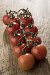 Pomodori a grappolo isolati su sfondo legno