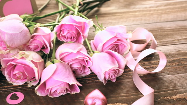 Pink roses and gift wrapped in recycled paper on rustic wood table