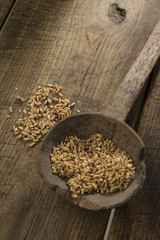 mestolo con grano su sfondo legno