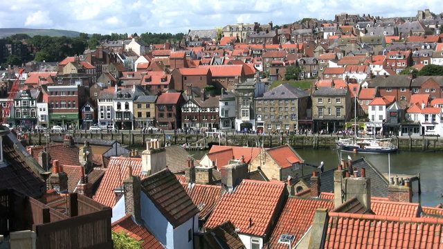 Church of St Mary and the Abbey sit high above the houses restaurants and shops of the port of Whitby North Yorkshire, 