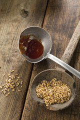 due mestoli da cucina con grano e sugo su un  sfondo tavola di legno scuro