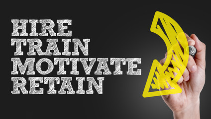 Hand writing the text: Hire - Train - Motivate - Retain