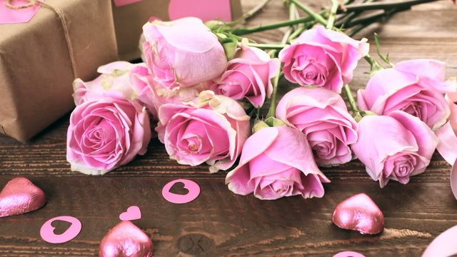 Pink roses and gift wrapped in recycled paper on rustic wood table