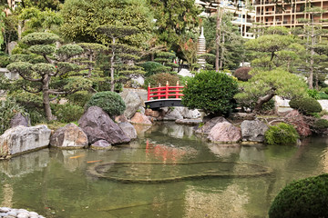 Japanese Garden in Monaco in the early morning. Part of the red bridge is hidden behind a bush