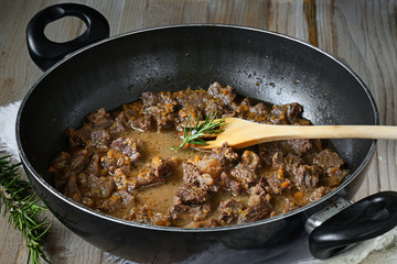 spezzatino di guanciale stufato in padella sfondo legno