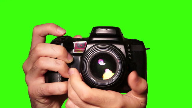 Photographer takes pictures with DSLR camera on a chroma key green screen.