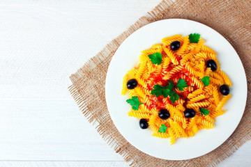 fusilli pasta and olives with parsley and ketchup in plate  on wooden white background