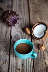 A Cup of coffee on wooden background, with coconut, a flower and