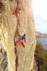 Young male climber hanging by a cliff.