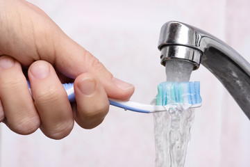 hand washing toothbrush under running water - Powered by Adobe