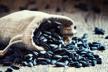 Sunflower seeds in a canvas bag, old wooden background, selectiv