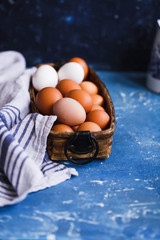 Eggs. Basket of eggs with linen cloth on a blue stone tabletop. 