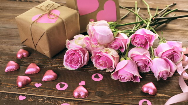 Pink roses and gift wrapped in recycled paper on rustic wood table