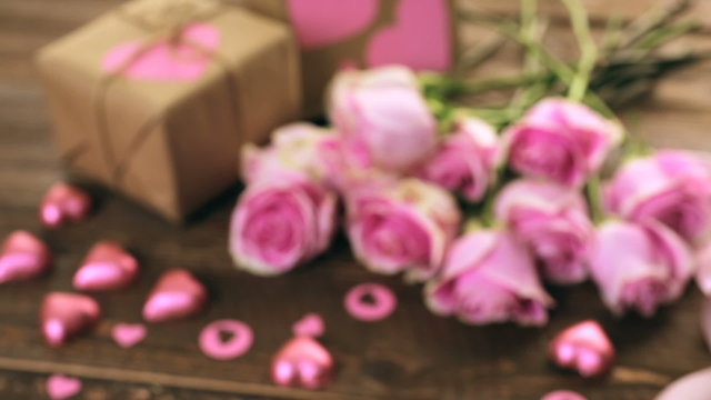 Pink roses and gift wrapped in recycled paper on rustic wood table