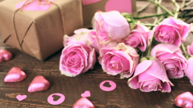Pink roses and gift wrapped in recycled paper on rustic wood table
