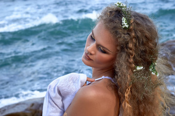  pretty curly woman portrait with flowers in head, sea view