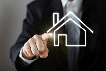 Businessman choosing house, real estate concept. Hand pressing the house icon. Copy space