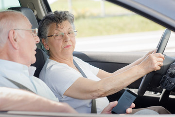 Elderly lady driving, husband talking to her