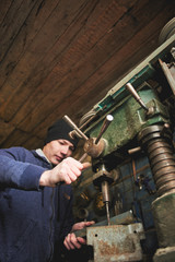 The young master works for the drill press in the workshop