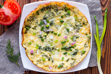 white plate with omelette on a napkin on a wooden background