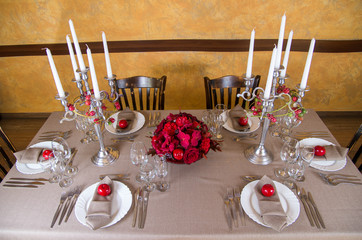 Festive table decorated with red flowers and fruit.
